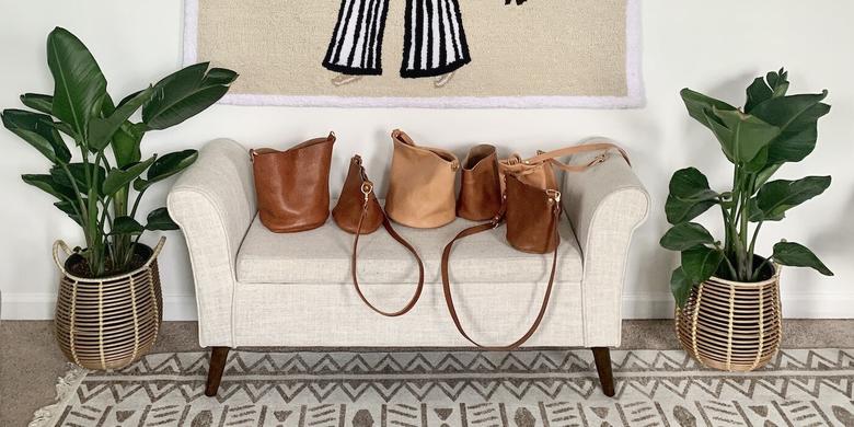leather bags lined up on a beige chair
