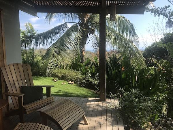 une vue depuis le porche avec une chaise longue et des palmiers