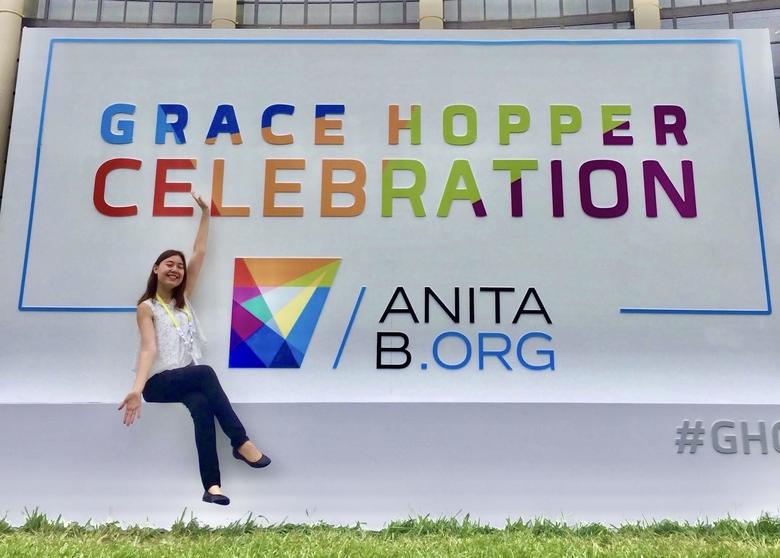 person posing in front of Grace Hopper Celebration conference sign