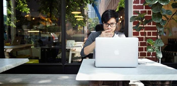 person sitting at an outdoor table working on a laptop