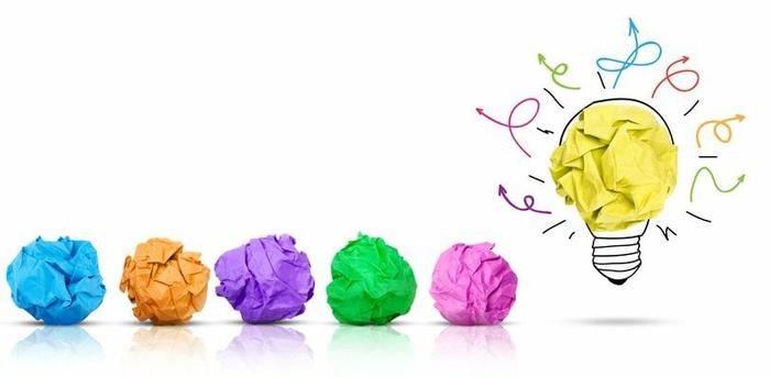 colorful balls of crumpled paper in a row with a yellow one to the right in an illustration of a light bulb