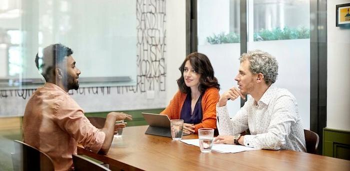 three people sitting at a conference table talking