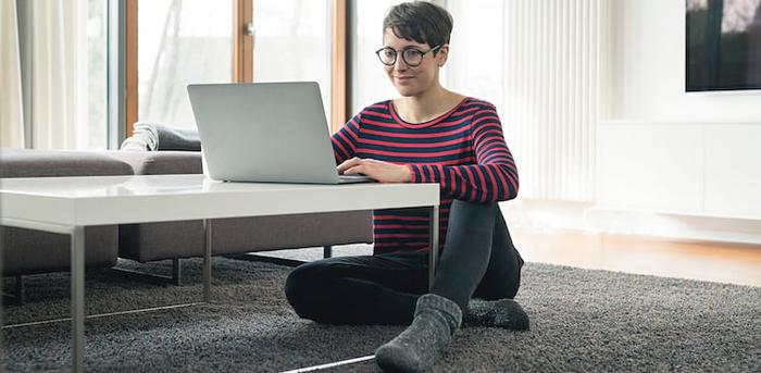 person sitting on floor at coffee table with laptop