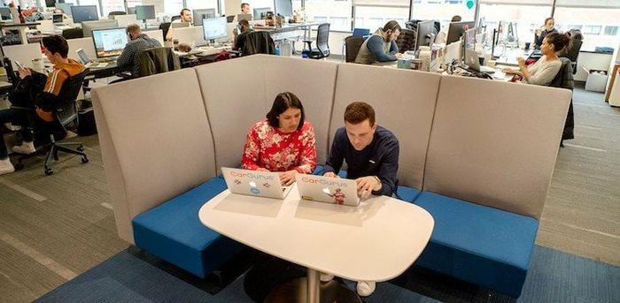 two CarGuru employees working on their laptops in the Cambridge office