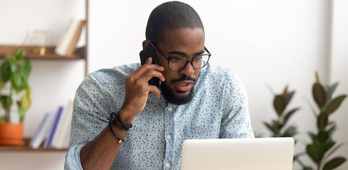 person on phone in front of laptop