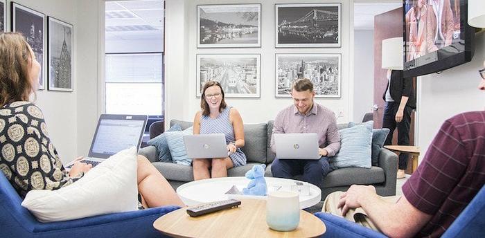 employees at Open Systems Healthcare working on laptops and laughing