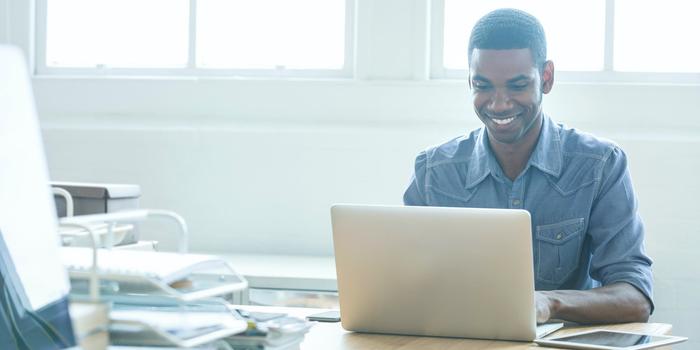 person sitting at a desk and working on a laptop