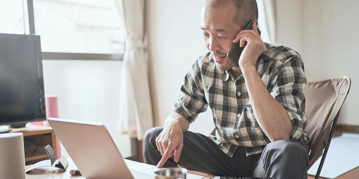 person on the phone while looking at computer