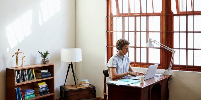 Person on laptop in home office with headphones on