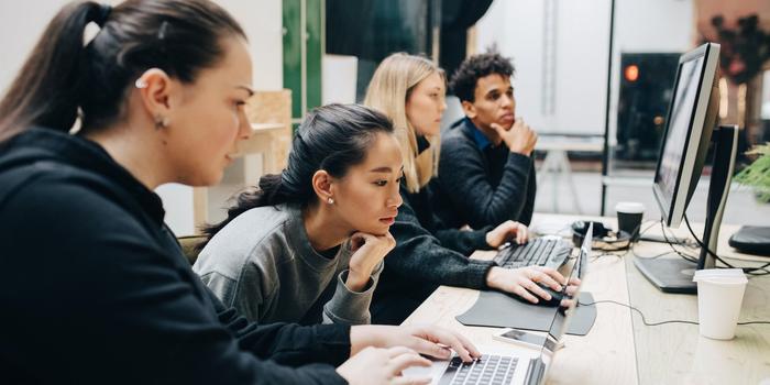 group of four software engineers looking at 2 computer screens