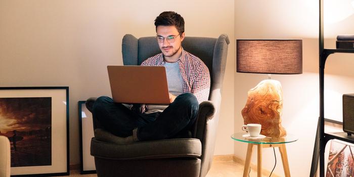 person working on laptop while sitting cross-legged on armchair