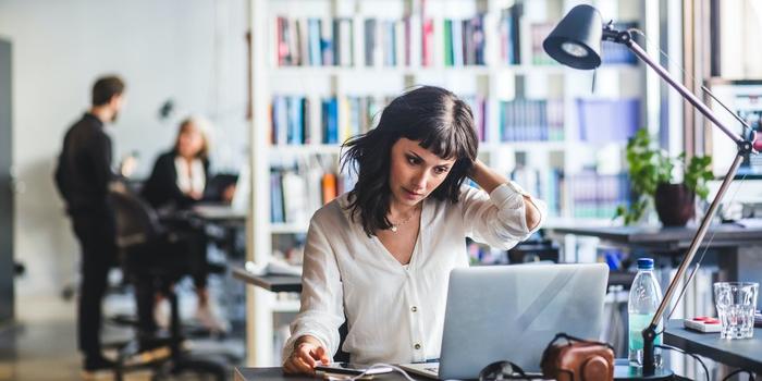 person working at laptop in office with out-of-focus coworkers in the background