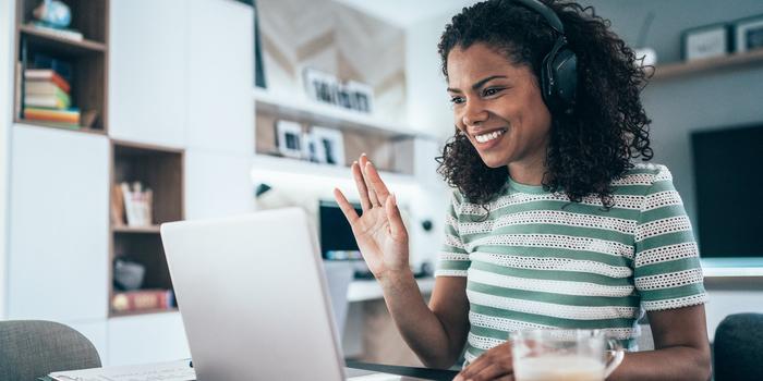 person waving to laptop during a video interview