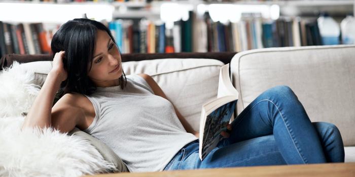 person relaxing on couch reading a book