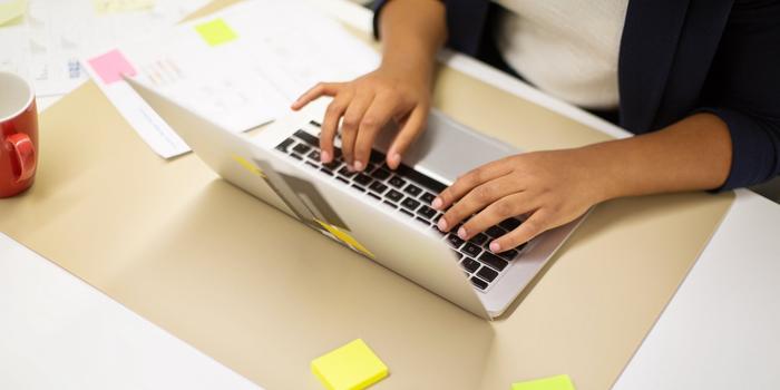 person's hands on laptop on desk at work