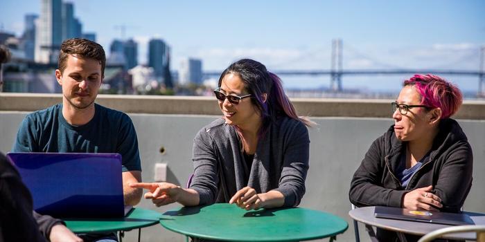 employees looking over a laptop from an office rooftop terrace