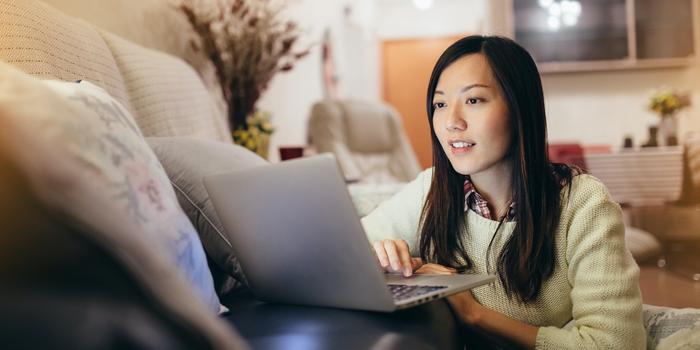 person sitting on floor using laptop on couch