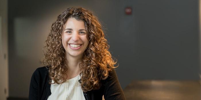 smiling personal with curly hair sitting at a table