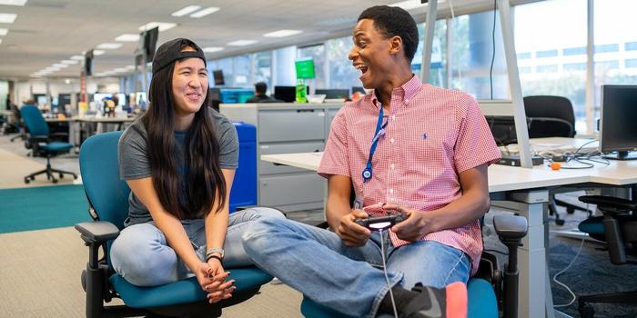 two employees laughing while playing video games in an office