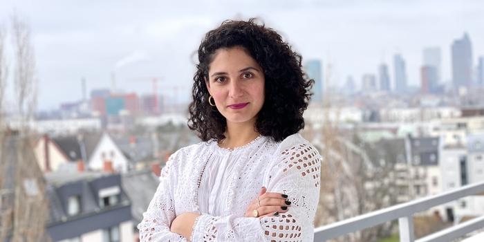 a person standing with their arms crossed in front of a cityscape