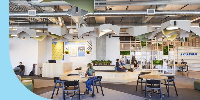 Atlassian employees sitting and working in a communal space in the company’s San Francisco office.