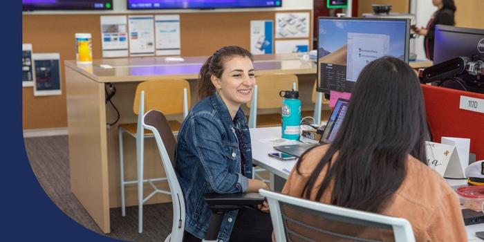 An Avanade employee having a conversation with a coworker by their desks.