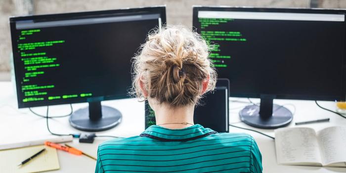 High angle view of engineer looking at code on a double-monitor desktop computer