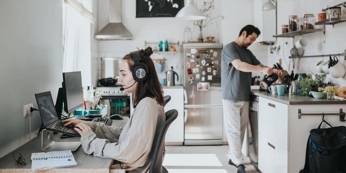 person working from home using headphones and a laptop stand