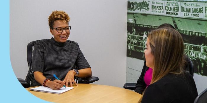 Three Healthfirst employees sitting at a small conference room table.