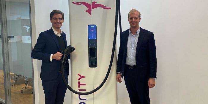 two people standing next to an IONITY electric vehicle charging station