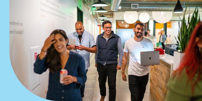 Four Instacart employees walking and laughing with a laptop out.