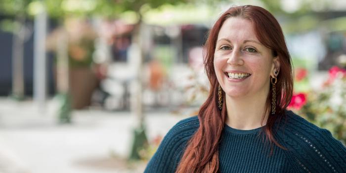 A person with long, red hair smiling