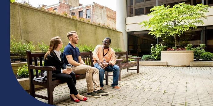 Kroger employees sitting on a bench in an outdoor courtyard