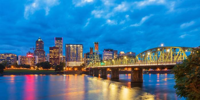 skyline view of Portland, Oregon, at dusk, with Willamette River and Hawthorne Bridge