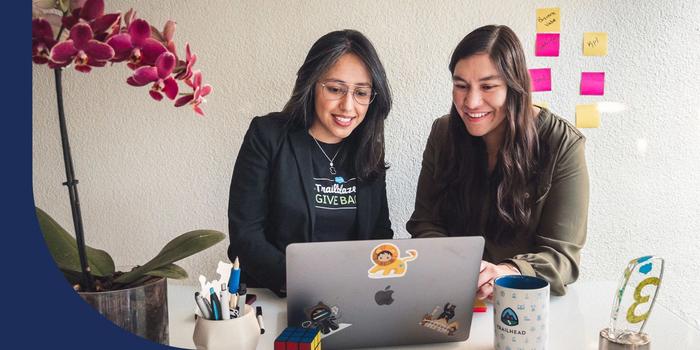 Two employees looking over a laptop together at a desk.