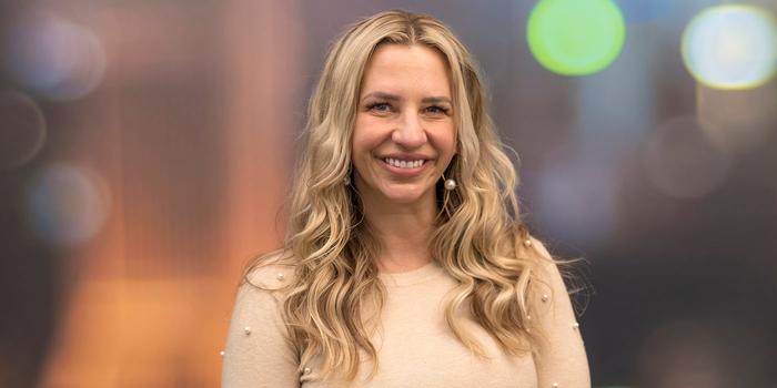 a headshot of a person with wavy blonde hair smiling