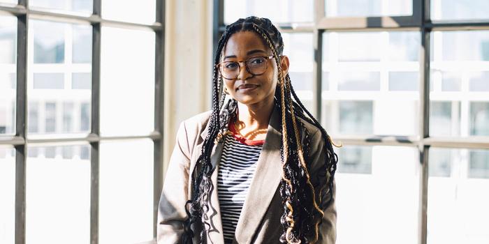 a person with long braids and eyeglasses in front of a window