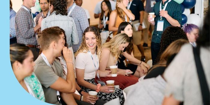 An Upside employee holding a cup of coffee while chatting with coworkers at a company celebration.