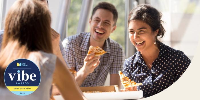 three people eating pizza and laughing