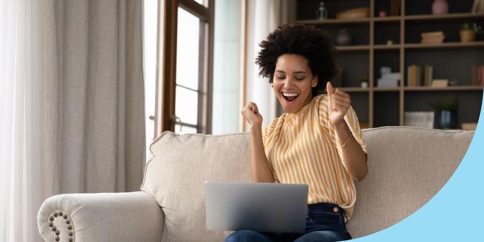 person sitting on the couch dancing while they read something on their laptop