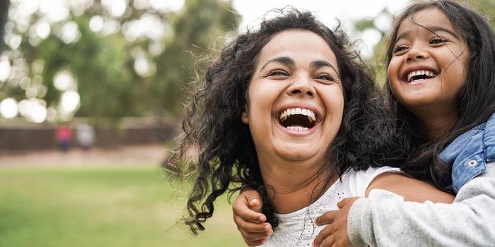 person carrying their child on their back in outdoor park, both laughing