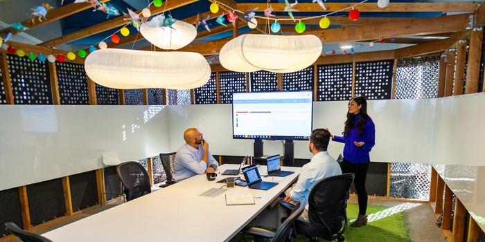 three people meeting in a conference room with colorful string lights hanging from the ceiling