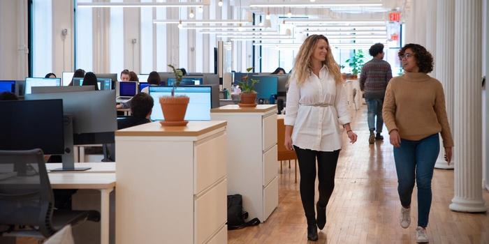 two people walking together in a open plan office space