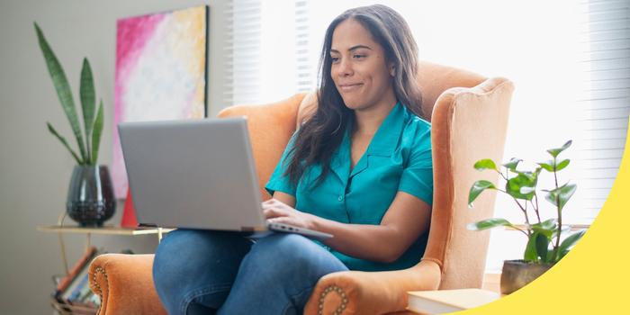 person sitting in an armchair while looking at a laptop