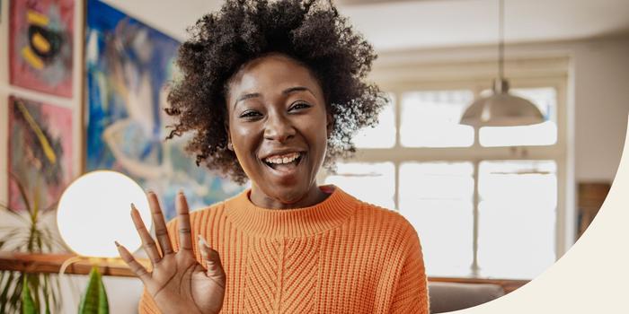 person in orange sweater waving and smiling