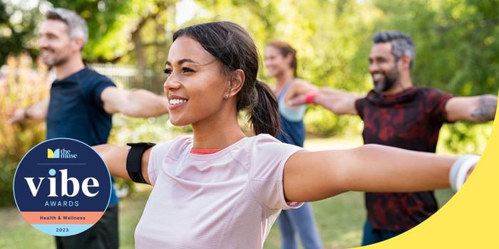 A woman smiling as she exercises outdoors in a group.