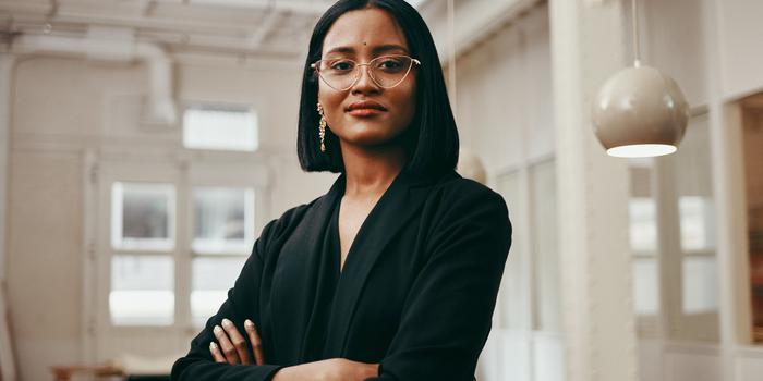 person standing in open office looking confident with arms crossed