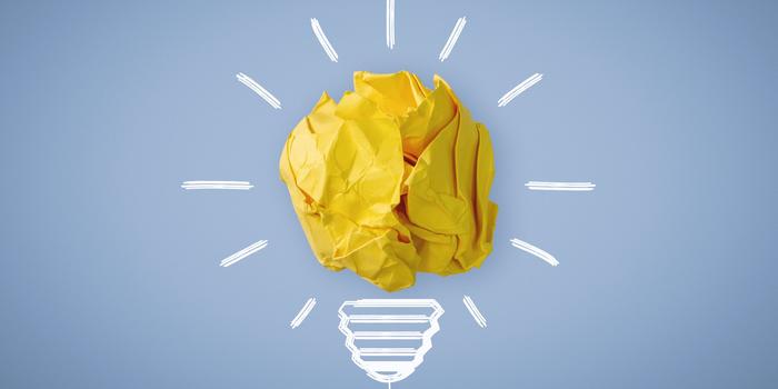 yellow crumpled ball of paper with white lines drawn around it to look like a light bulb against a blue background