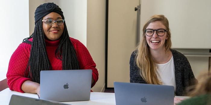 two people sitting in a table with their laptops