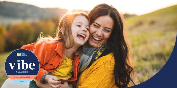 A mother and daughter embracing and laughing outdoors.